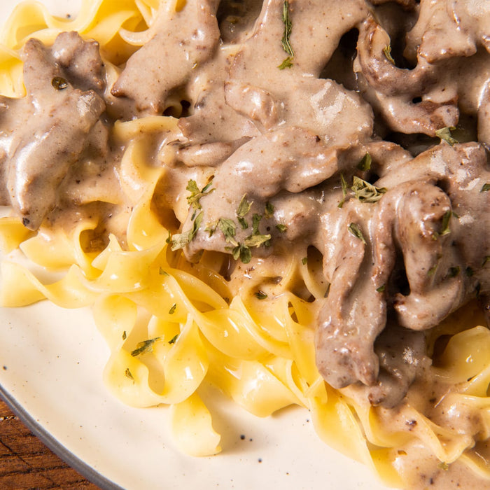 ['A close-up of a plate of creamy beef and noodles.']