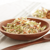 A wooden bowl filled with coleslaw.