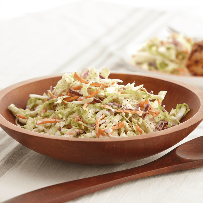 A wooden bowl filled with coleslaw.