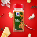 McCormick Salad Supreme seasoning bottle on a red background with food ingredients.
