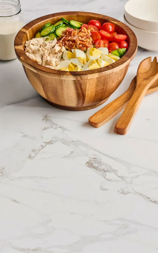 Wooden salad bowl with mixed salad on a marble countertop