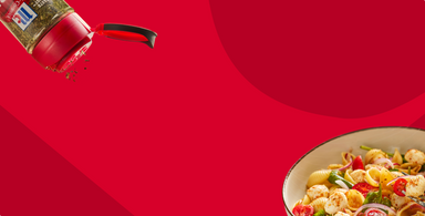 Spice shaker and bowl of pasta on a red background