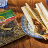 A bag of PoK brand tamale seasoning next to a plate of tamales.