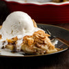 A slice of apple pie topped with a scoop of vanilla ice cream.