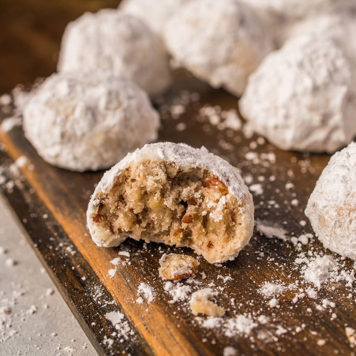 A close-up of pecan sandies on a wooden cutting board.