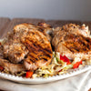 Grilled pork chops with cabbage and red peppers on a white plate.