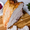 A close-up of a roasted turkey breast on a wooden cutting board.