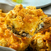 A close-up of a casserole dish filled with a cheesy, meaty breakfast casserole.