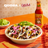 QDOBA salad with Cholula hot sauce bottle on an orange tablecloth