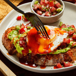 A plate of avocado toast topped with a fried egg and salsa, showcasing a delicious and visually appealing breakfast or brunch option.