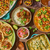 A festive spread of Mexican cuisine featuring tacos, enchiladas, and a shrimp dish, with a bottle of Cholula Green Sauce 12 Fl Oz prominently displayed among other condiments.