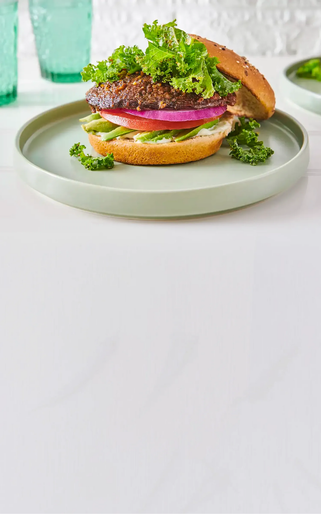 Delicious burger with lettuce, tomato, and onion on a green plate against a white background