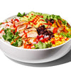 A white bowl filled with a colorful salad with chicken, avocado, corn, black beans, and red onion.