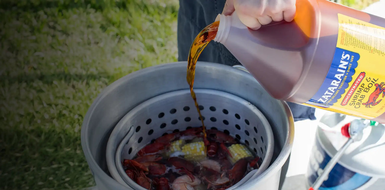 Pouring Zatarain's Concentrated Shrimp & Crab Boil into a pot of crawfish and corn outdoors