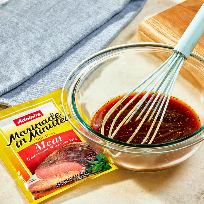 A bowl of Adolphs Marinade in Minute Meat Tenderizing Marinade Mix with a whisk.