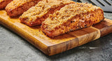 Breaded salmon fillets on a wooden cutting board with a gray background
