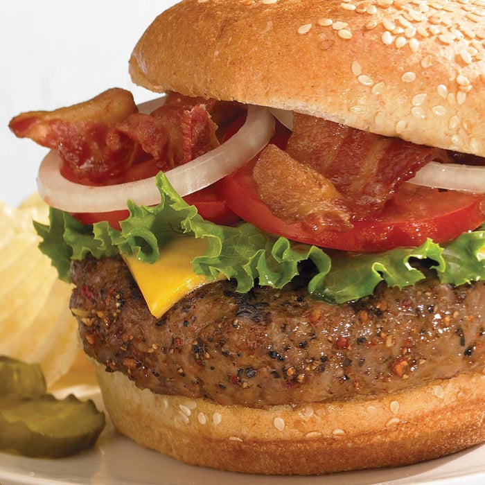 A close-up of a cheeseburger with bacon, lettuce, tomato, and onion.
