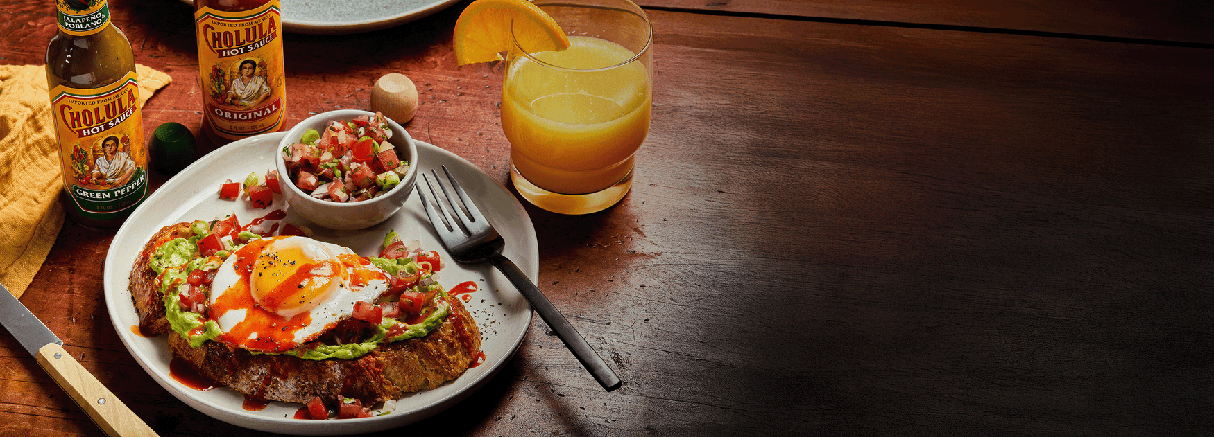 Breakfast spread with eggs, toast, salsa, and a glass of orange juice on a wooden table.