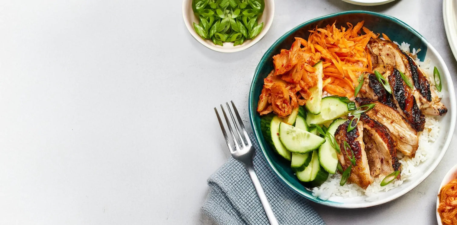 Bowl of food with rice, vegetables, and meat on a white background