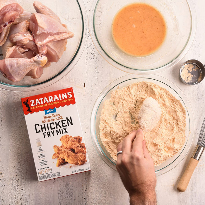 A hand dips a chicken drumstick into a bowl of Zatarains Southern Buttermilk Chicken Fry Mix.