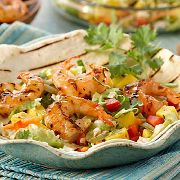 A bowl of shrimp salad with mango, red peppers, and cilantro.