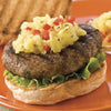 A juicy burger topped with pineapple salsa sits on a toasted bun with lettuce, presented on an orange plate.