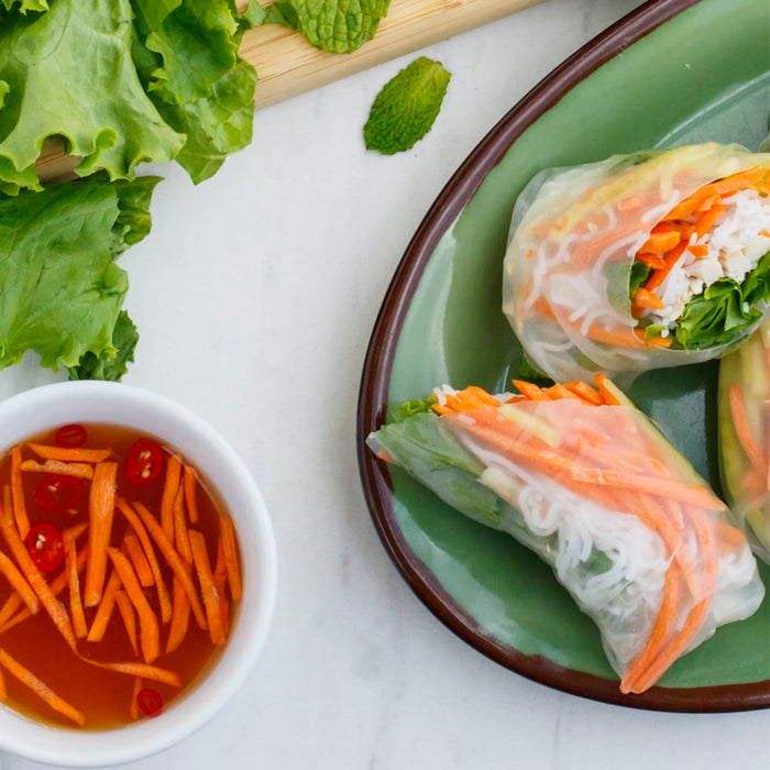 A plate of spring rolls with a side of dipping sauce.