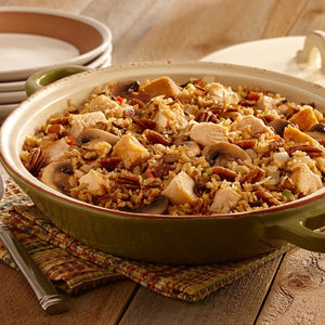 A close-up of a bowl of chicken and wild rice casserole with pecans and mushrooms.