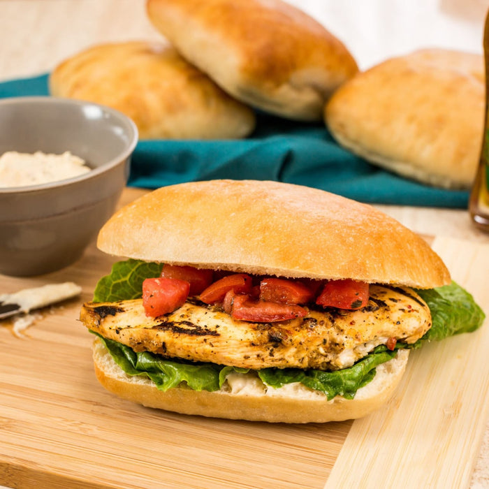 A delicious-looking chicken sandwich with lettuce and tomatoes sits on a wooden cutting board, ready to be enjoyed.