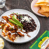 A plate of El Guapo Chile Quebrado with black beans, avocado, and crema fresca.