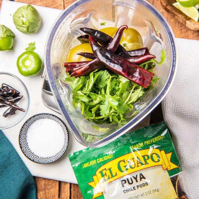 A close up of a blender filled with ingredients for El Guapo Puya Chile Pods salsa.