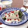 A plate of chiles rellenos topped with a creamy sauce and pomegranate seeds.