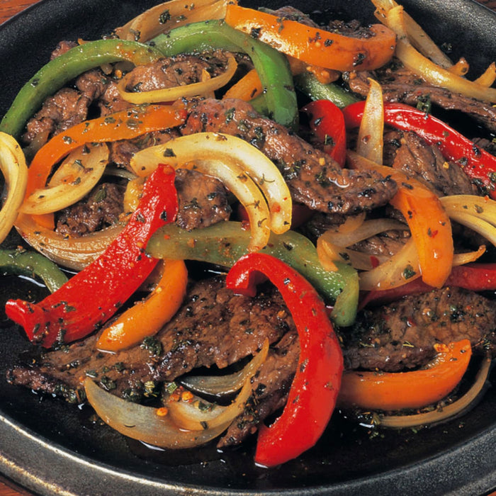 A close-up of a plate of beef stir-fry with peppers and onions.