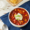 A bowl of chili topped with avocado and sour cream.