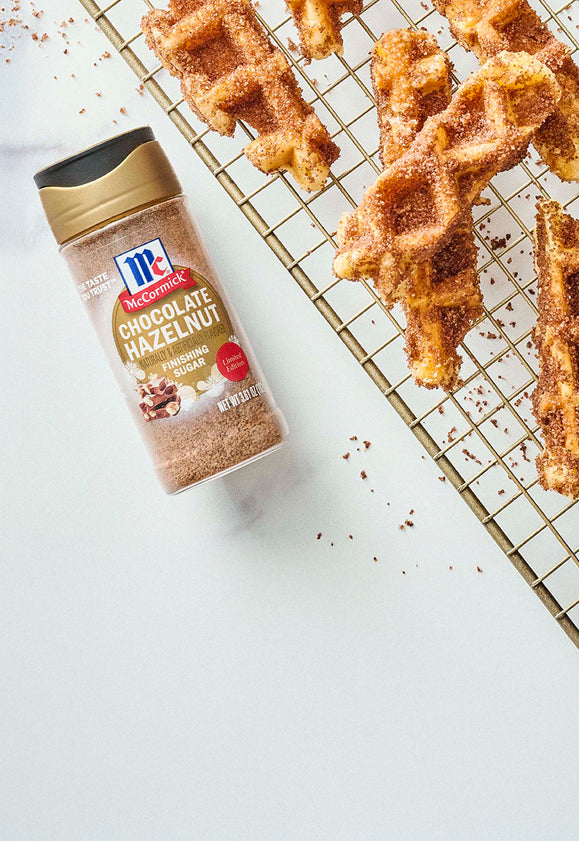 McCormick Chocolate Hazelnut Finishing Sugar next to waffle sticks coated in chocolate hazelnut sugar on a cooling rack
