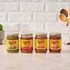 Four jars of Cholula salsa in different flavors, including Salsa Verde, Original Hot, Original Medium, and Smoky Chipotle, are arranged on a table against a textured white brick wall.