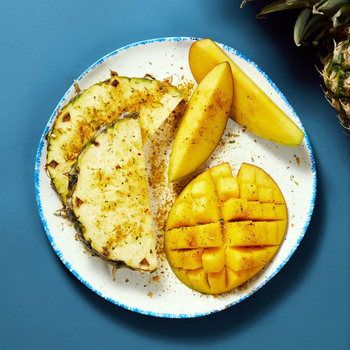A plate of pineapple and mango slices seasoned with spices.