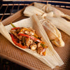 A close up of a tamale with chicken and peppers inside a corn husk.