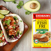 A box of Zatarains Fish Fri Crispy Cajun Seafood Bread Mix next to a plate of fish tacos.