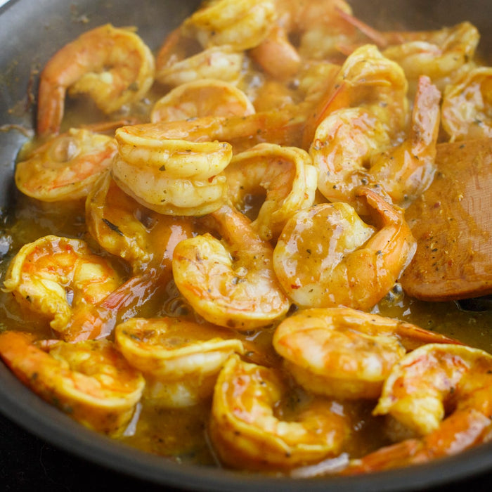 A close-up of a pan of cooked shrimp in a creamy sauce.