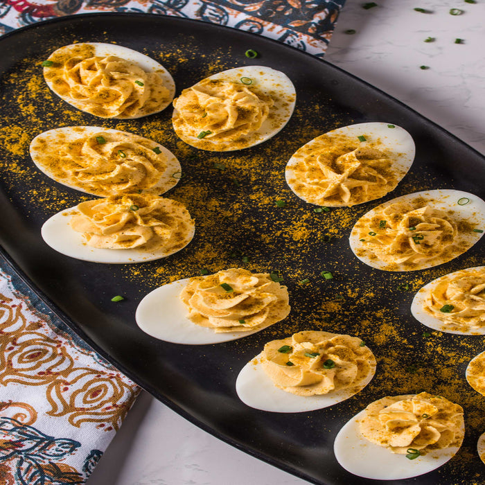 A plate of deviled eggs with curry powder sprinkled on top.