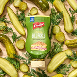 dill pickle mustard spread surrounded by pickles and dill on a wooden table