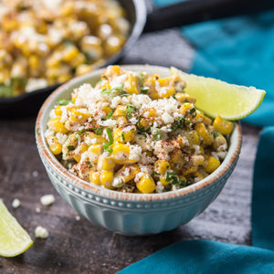 A bowl of Mexican street corn salad with cotija cheese lime and cilantro.