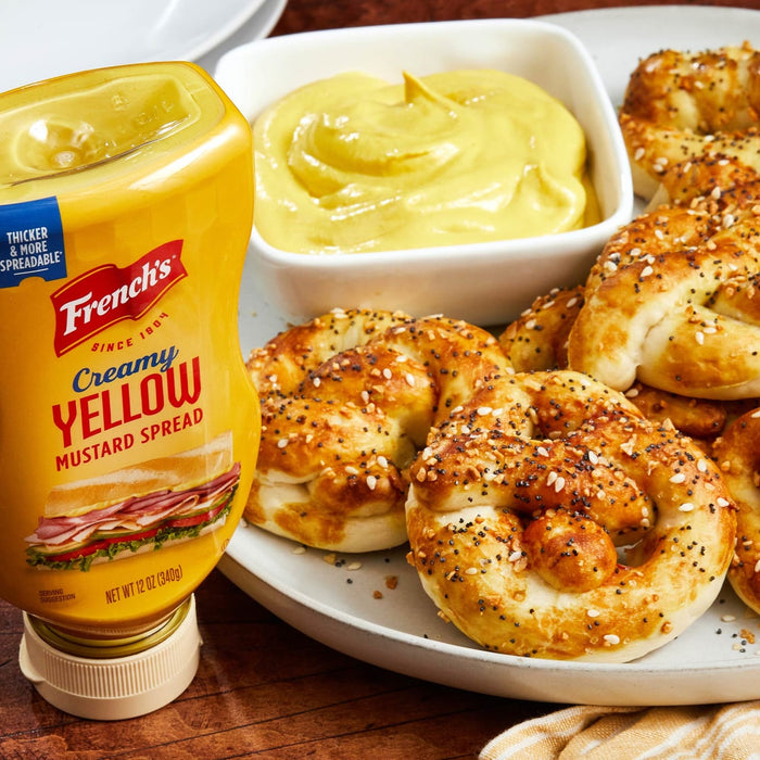 A bottle of Frenchs Creamy Yellow Mustard next to a plate of pretzel bites with a small bowl of mustard.