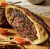A close up view of a grilled pita bread pocket stuffed with a seasoned meat filling and fresh herbs as part of a recipe for .
