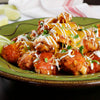A plate of chicken wings covered in cheese, sour cream, and cilantro.