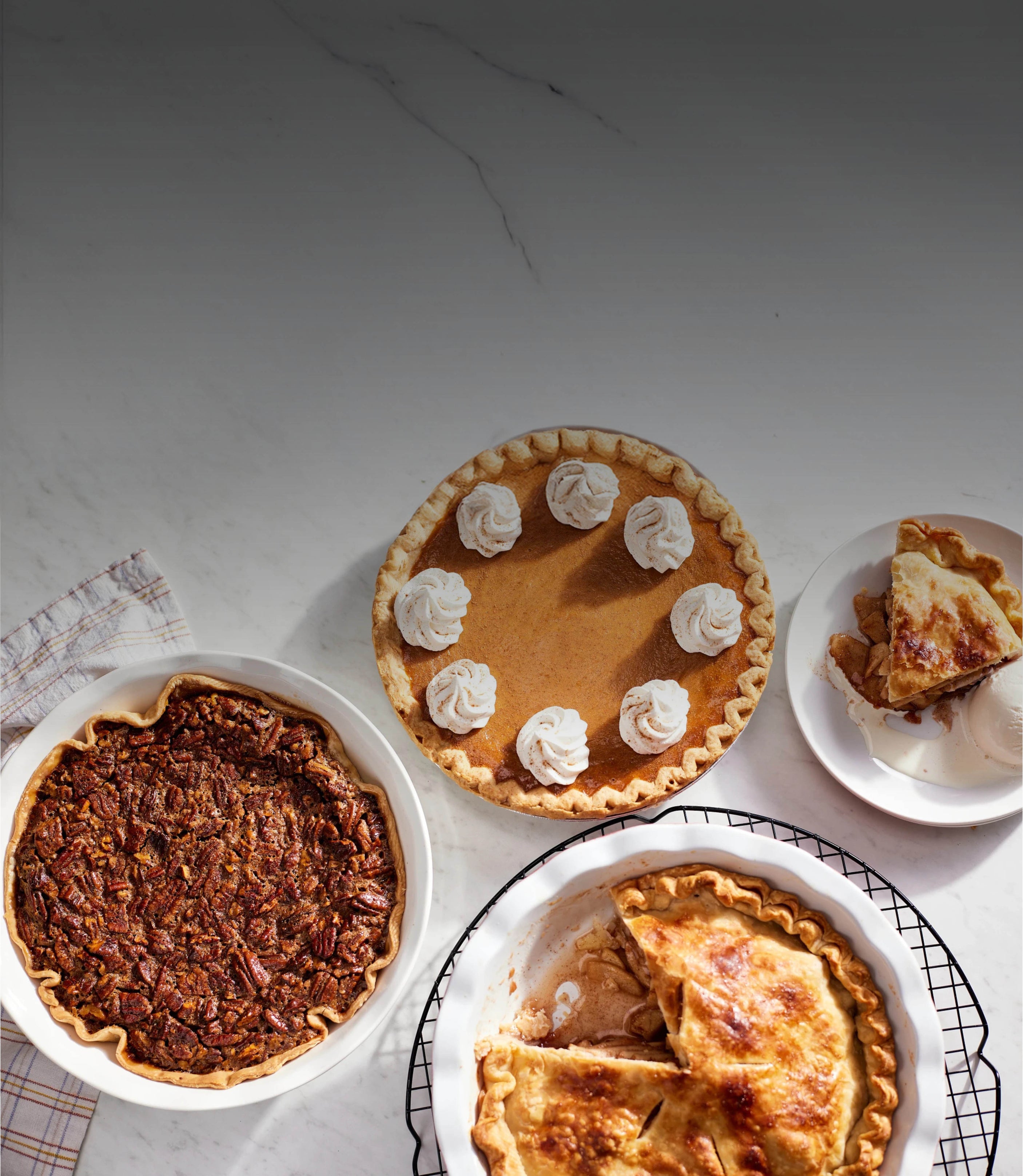 Three pies on a marble surface with a slice removed from one pie.
