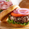 A close-up of a juicy burger with lettuce, tomato, red onion, and a beef patty.