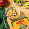 A bowl of Cholula Salsa Verde Chicken Burrito Bowl with a fork and other ingredients on the side.