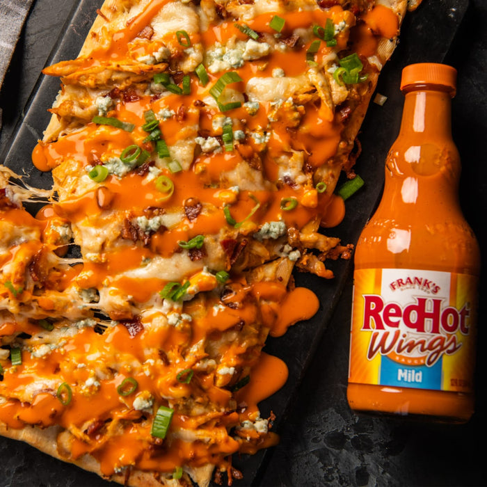 A close-up of a pizza topped with chicken, bacon, blue cheese, and Franks RedHot Wings sauce.